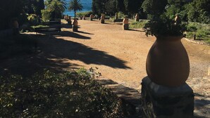 Un jardí amb una banca, un vas gran i vista al mar.