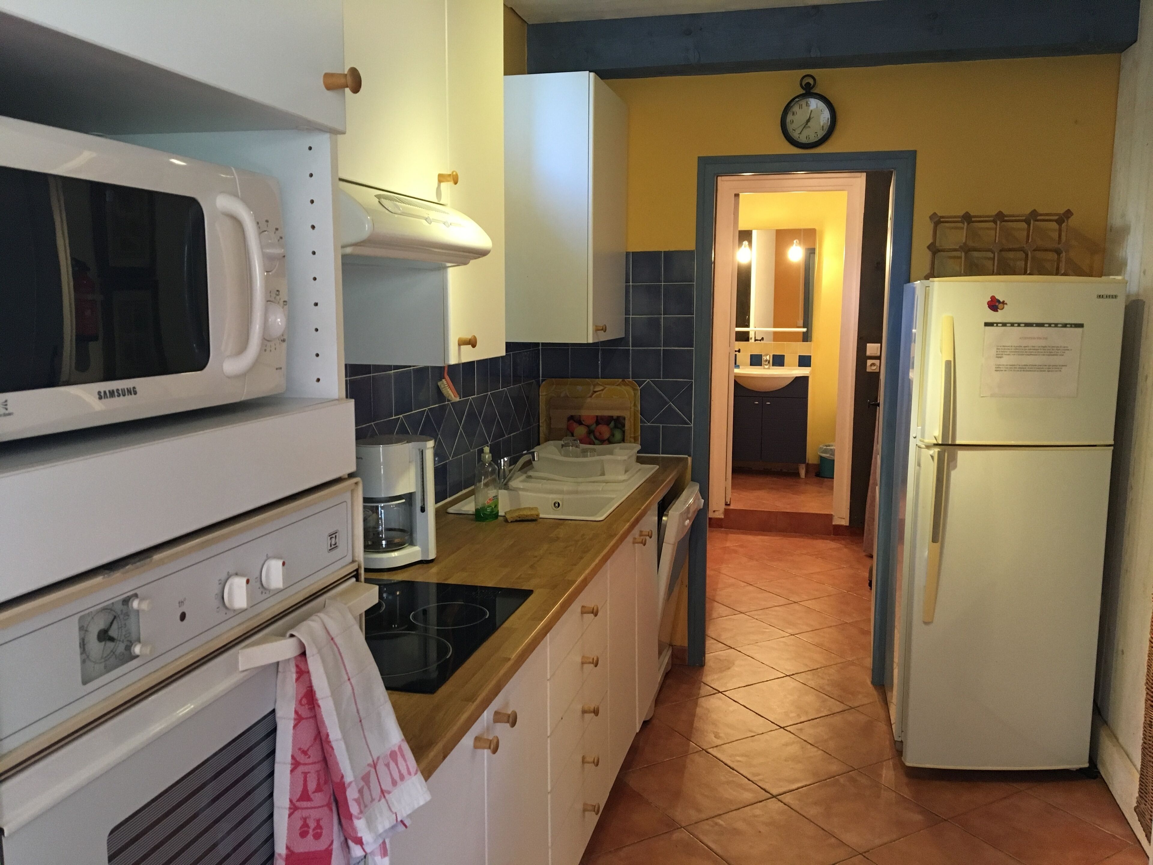 A compact kitchen with a microwave, stove, coffee maker, and a refrigerator.