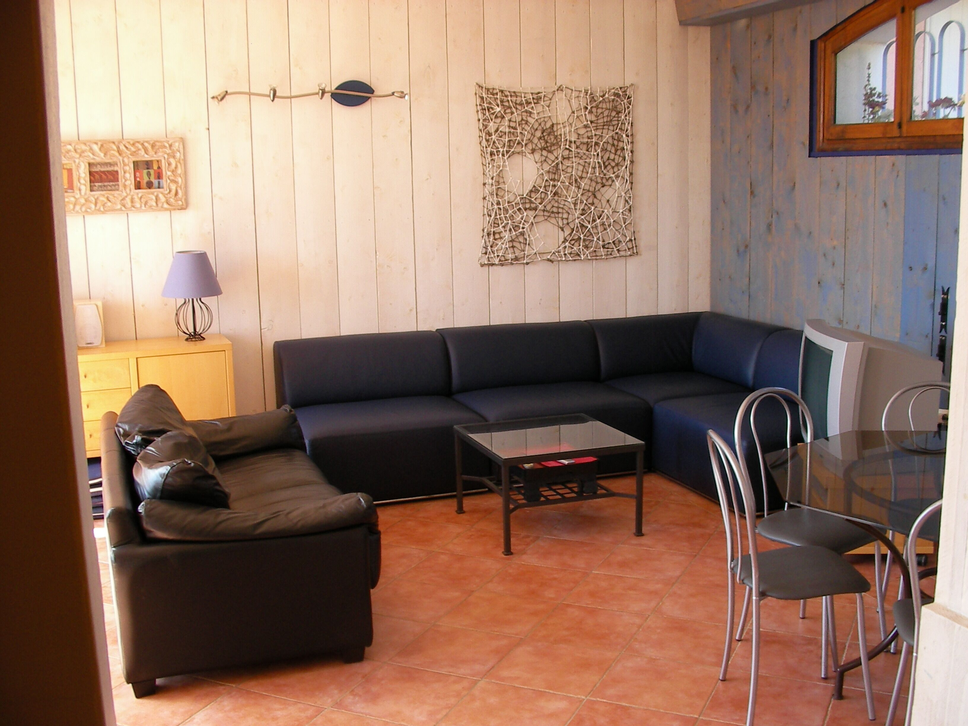 A living room with a sectional sofa, a coffee table, and a dining area with chairs.