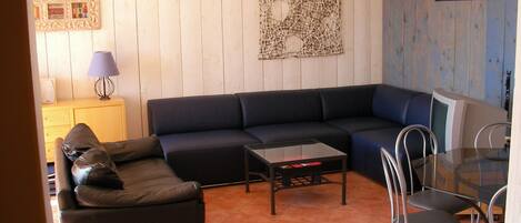 A living room with a sectional sofa, a coffee table, and a dining area with chairs.