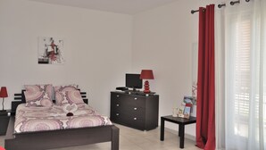 A bedroom with a bed, a dresser, a nightstand, a lamp, a window with curtains, and a wall-mounted artwork. - Furnished studio, near beach and town center, WIFI  (Annecy)