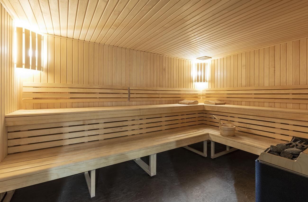 Un sauna avec des bancs en bois et un banc muni d’un seau.