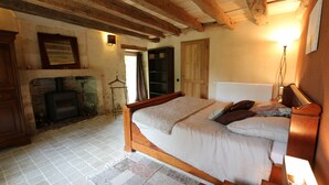 Een slaapkamer met een houten bed, een open haard en een betegelde vloer.