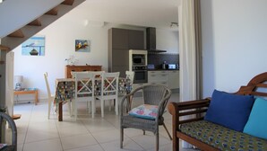 Amplia sala de estar con una mesa de comedor, sillas, un sofá y una escalera que sube a otro nivel.
