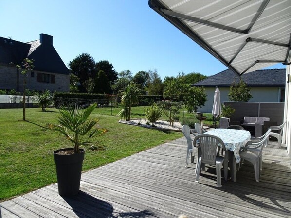 A wooden deck with outdoor furniture, a covered area, and a well-maintained lawn.