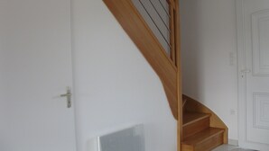 Un escalier en bois avec une rampe métallique menant à un palier.