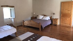 A bedroom with a wooden bed, a smaller bed, a nightstand, a lamp, a window, and a wooden wardrobe. - Gite des Baragnas in the heart of Cévennes nature, air-conditioned, internet, swimming pool (Saint-Jean-Du-Gard)