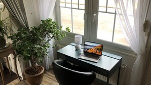 Un espace de travail avec un ordinateur portable sur un bureau, une plante en pot et une chaise.