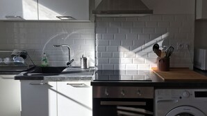 Moderni keittiö, jossa on sisäänrakennettu uuni ja astianpesukone, ruostumattomasta teräksestä valmistettu allas ja puinen työtaso.