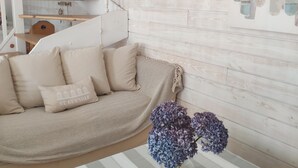 A cozy living room with a sofa, a vase with flowers, and a striped tablecloth. - Pretty, well-equipped house, close to the sea and fishing port, ideal for children. (Penmarch)