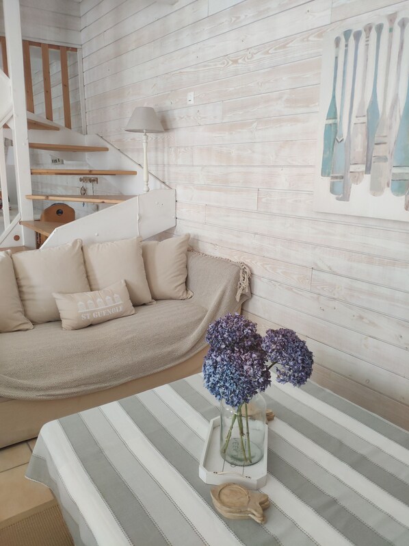 A cozy living room with a sofa, a vase with flowers, and a striped tablecloth.