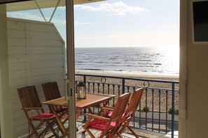 Un balcon avec vue sur la plage, des meubles en bois et une balustrade.