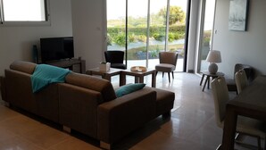 A modern living room with a sofa, a TV, and a dining area with chairs and a table. - HOUSE WITH SUPERB SEA VIEW IN ROSCOFF - 4 STARS (Roscoff)