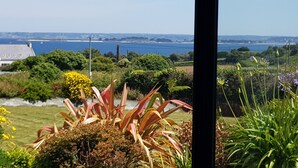 A view of a coastal landscape with a body of water, greenery, and a building with a sloped roof. - HOUSE WITH SUPERB SEA VIEW IN ROSCOFF - 4 STARS (Roscoff)