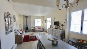 Uma sala ampla com uma mesa de jantar, cadeiras, um sofá e uma lareira.