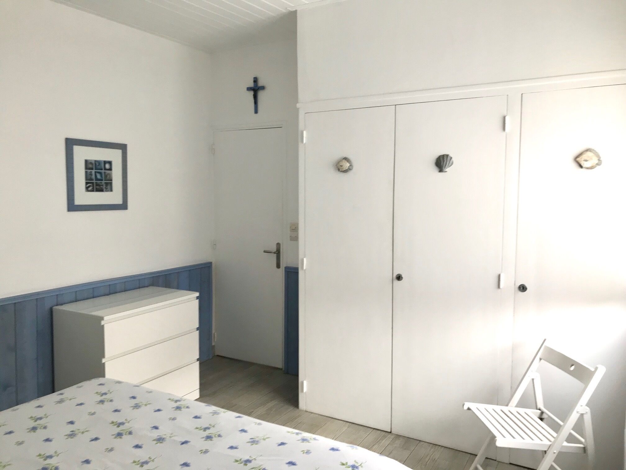 A bedroom with a bed, a dresser, a wardrobe, and a chair.