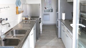 Cozinha moderna com eletrodomésticos de aço inoxidável, armários brancos e painel de azulejos.