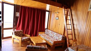 A cozy room with wooden furniture, a red curtain, and a ladder against the wall. - Studio for rent located in heart of French Alpes for up to 5 people (Orcières)
