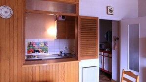 A kitchen with wooden cabinets, a tiled backsplash, and a microwave. - Studio for rent located in heart of French Alpes for up to 5 people (Orcières)