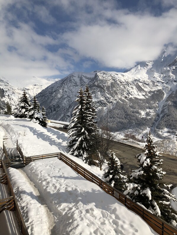 A snow-covered mountain landscape with a wooden bridge and snow-laden trees. - Studio for rent located in heart of French Alpes for up to 5 people (Orcières)