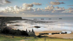 A coastal landscape with a beach, a cliff, and a small building with a tower. - Quiet House 300m Landing Beach 6 Pers (Asnelles)