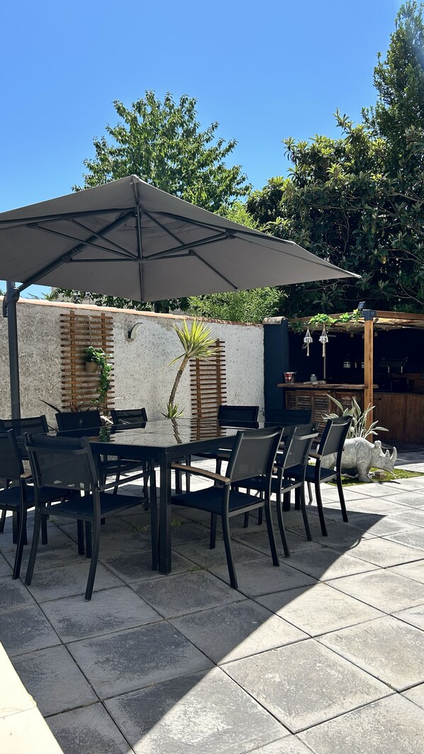An outdoor patio with a table and chairs, a pergola, and a wall with plants. - Air-conditioned villa with a private pool and hot tub, in the Camargue (Garons)
