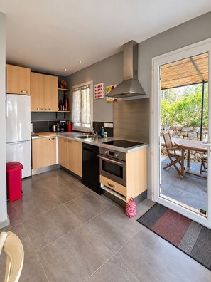 A modern kitchen with stainless steel appliances, wooden cabinets, and a large window.