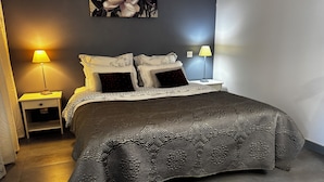 Ein Schlafzimmer mit einem großen Bett, zwei Nachttischen, einer Wandlampe und einem Blumenbild.