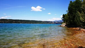 Ein klarer See mit sichtbarer Unterwasservegetation und einem entfernten Gebirge.