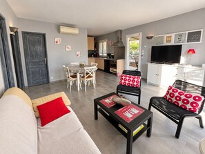 A modern living room with a sofa, a coffee table, and a dining area with a table and chairs.