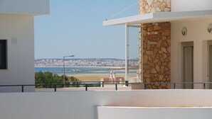 Un bâtiment moderne doté d’une façade en pierre et d’un balcon offrant une vue sur la plage et le paysage urbain.