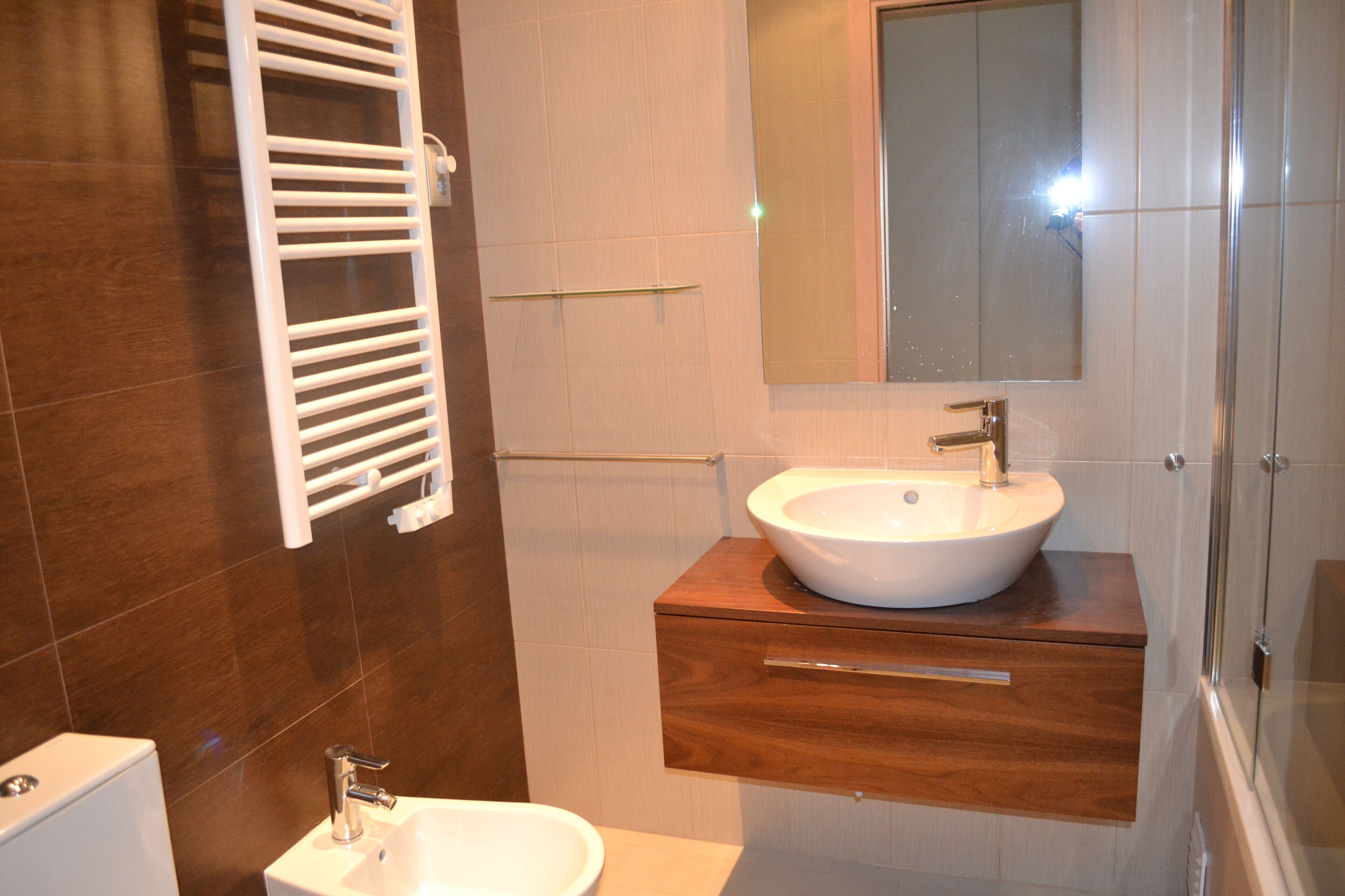 Un baño con un lavamanos blanco, un espejo y un toallero.