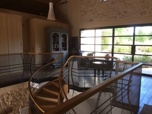 A spacious room with a large window, a staircase, and a dining area with a table and chairs.