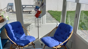 A room with two blue cushioned chairs, a small octagonal table, and a bulletin board with various items. - Beautiful house typical from Oleron (Saint-Pierre-D'oléron)