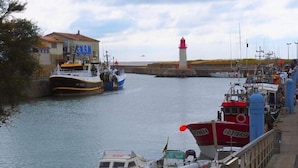 A harbor with boats docked, a lighthouse in the background, and a building with 'NSM' signage. - Beautiful house typical from Oleron (Saint-Pierre-D'oléron)