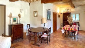 A rustic dining area with a wooden table and chairs, a cabinet, and a tiled floor.
