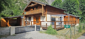 A wooden chalet with a balcony, a covered porch, and a sign indicating 'Le Chalet Melgueil'.