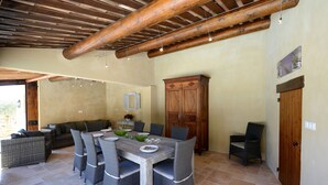 A dining area with a wooden table, wicker chairs, and a cabinet. - VINEYARDS AND OLIVE TREES BETWEEN ON THE WINE ROUTE (Vacqueyras)