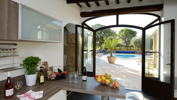 A kitchen with a view of a swimming pool and outdoor seating. - VINEYARDS AND OLIVE TREES BETWEEN ON THE WINE ROUTE (Vacqueyras)