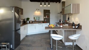 A modern kitchen with a built-in refrigerator, a central island with bar stools, and a wooden ceiling. - VINEYARDS AND OLIVE TREES BETWEEN ON THE WINE ROUTE (Vacqueyras)