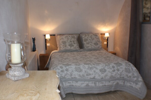 A bedroom with a bed, two bedside lamps, a nightstand, and a decorative candle holder.