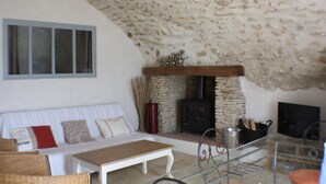 A cozy living room with a stone fireplace, a sofa, a coffee table, and a TV.