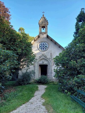 A church with a bell tower, a circular stained glass window, and a gravel path leading to the entrance.