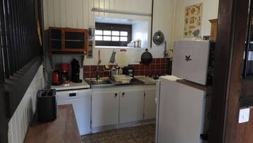 A compact kitchen with white cabinets, a sink, a stove, and a refrigerator.