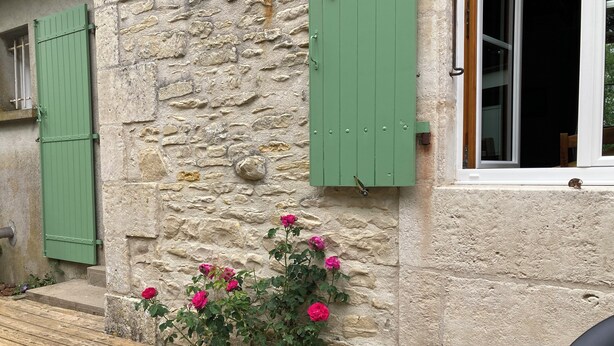 A stone building with green shutters, a window, and a flower box with pink flowers. - Witihin the marais poitevin, house with character is an enjoyable place to stay (Damvix)