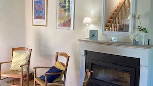 A cozy living room with a fireplace, wooden chairs, a rug, and two framed artworks on the wall. - Witihin the marais poitevin, house with character is an enjoyable place to stay (Damvix)