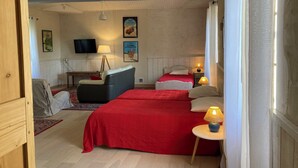 A cozy room with two beds, a sofa, a TV, and a small table with a lamp. - Witihin the marais poitevin, house with character is an enjoyable place to stay (Damvix)
