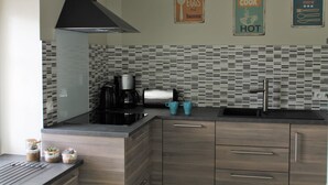 A modern kitchen with a black range hood, a coffee maker, and two teal mugs on the counter. - House on the outskirts of Saint Malo and on the banks of the Rance, 2 bedrooms, 2 bathrooms  (Saint-Jouan-Des-Guérets)