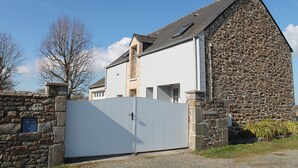 A stone building with a white garage door, a stone chimney, and a clear blue sky. - House on the outskirts of Saint Malo and on the banks of the Rance, 2 bedrooms, 2 bathrooms  (Saint-Jouan-Des-Guérets)