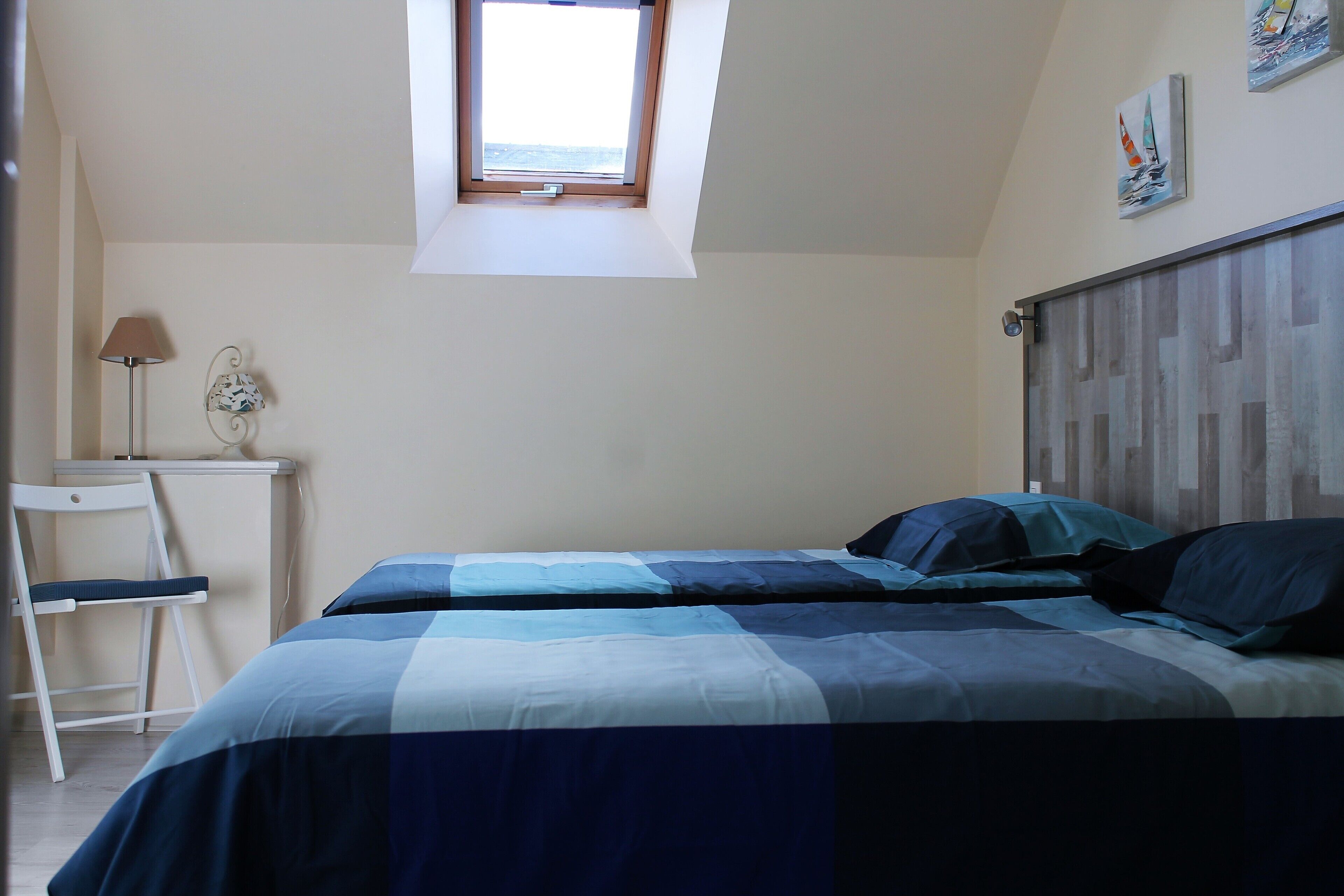 A bedroom with a bed, a desk, and a chair.
